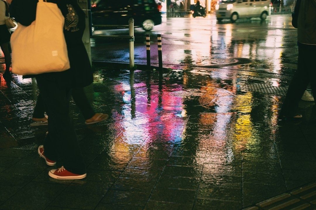 Fotgängare på en regnvåt stadsgata med färgstarka neonreflektioner